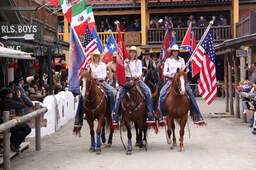 Eine Gruppe von Menschen reitet auf Pferden durch die Straßen von Pullman City Western town im Bayerischen Wald.